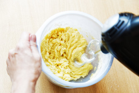Cook kneads the dough with a electric mixer. Personal point of view. Shallow focus.