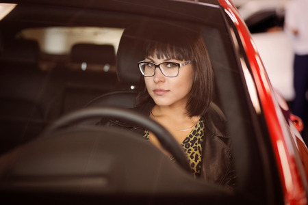 Portrait of brunette woman driving a car. Shallow focus. Toned image.の写真素材