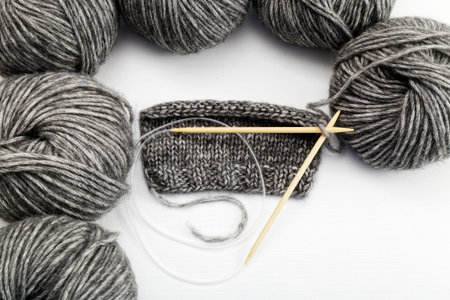 Balls of yarn for knitted handicrafts and knitting needles on white table. Top view. Copyspace.