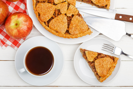 Homemade apple pie with cinnamon and cup of tea on white wooden table. Top view.の写真素材