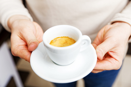 Closeup male hands holding a white cup of coffee espresso. Shallow focus.の写真素材