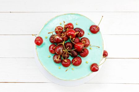 Cherry decorated homemade cake on white wooden table. Top view.の写真素材