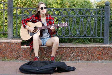 Ulyanovsk, Russia - July 26, 2019: Street musician young woman playing acoustic guitar and singing in a city parkのeditorial素材