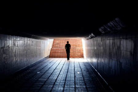 Dark silhouette of a man at the end of an underpass tunnel