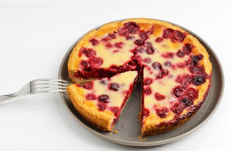 Closeup homemade berry pie with yogurt filling on white wooden table. Angle view. Shallow focus.の写真素材