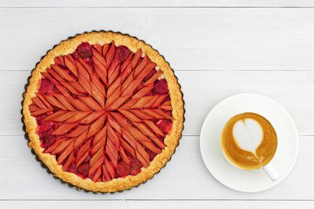 Homemade rhubarb and strawberry pie and cup of coffee on white wooden table. Top view.の写真素材