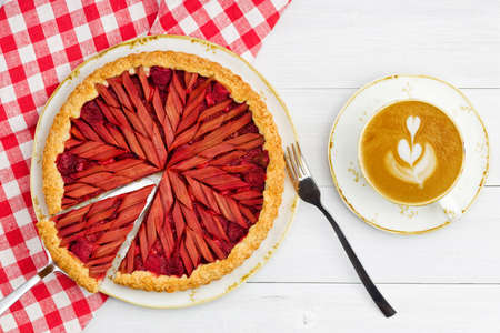 Homemade rhubarb and strawberry pie and cup of coffee on white wooden table. Top view.の写真素材