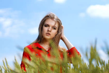 Portrait of young girl on a rye field against blue sky on background. Shallow focus.の写真素材
