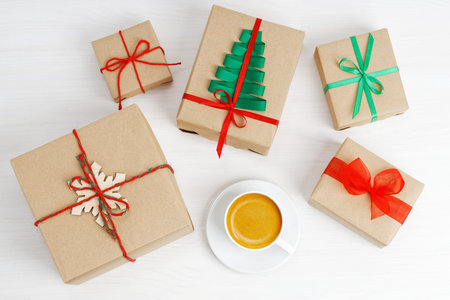Group of gift boxes wrapped in kraft paper, tied with twine and decorated with a ribbons on white wooden table.の写真素材