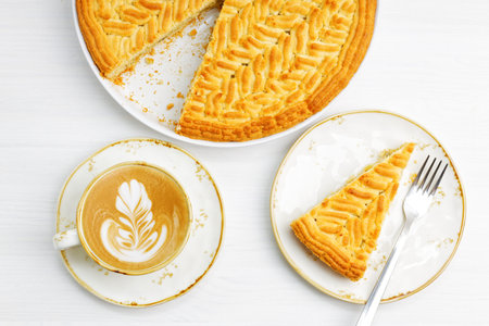Homemade gooseberry lemon pie and cup of coffee cappuccino on white wooden table. Top view.