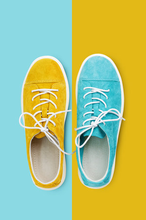 New yellow and blue suede walking shoes on yellow and blue background. Top view.