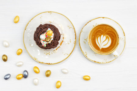Homemade Easter cake decorated with candies in the form of Easter eggs on white wooden table. Top...
