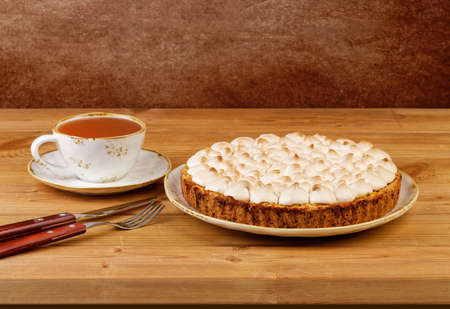 Homemade pie decorated with meringue and a cup of tea on a wooden table. Copyspace.の写真素材