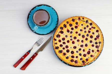 Homemade berry pie with ricotta and black currant and cup of tea on white wooden table. Top view.の写真素材