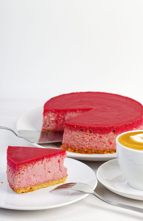 Homemade raspberry and strawberry cheesecake and cup of coffee cappuccino on white wooden table. copyspace.の写真素材