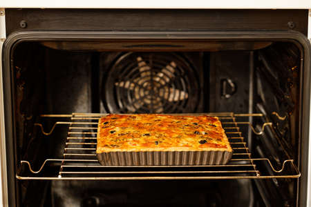 Homemade cheesy Quiche with tomatoes, champignons and olives baked in a home oven. Shallow focus.の写真素材