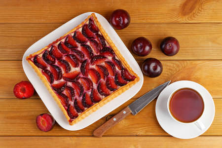 Homemade plum cake and cup of tea on wooden table. top view.の写真素材