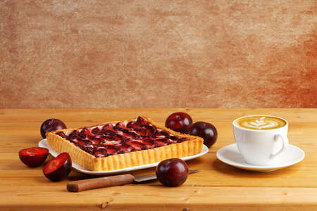 Homemade plum cake and cup of coffee cappuccino on wooden table. copyspace.の写真素材
