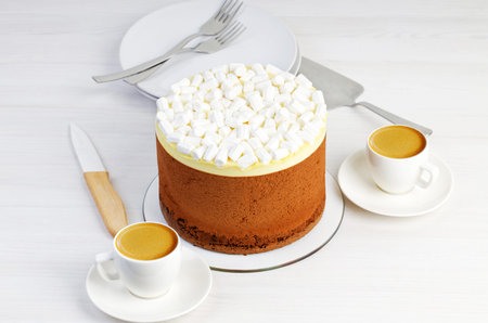A chocolate homemade pie decorated with a marshmallow and two cups of coffee espresso on a white wooden table. Shallow focusの写真素材