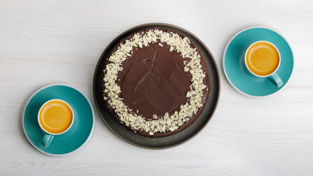 Homemade chocolate cheesecake and two cups of coffee espresso on white wooden table. Top view.