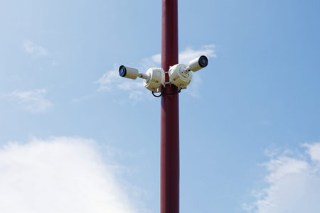 Two security cameras on the pillar against blue sky on background