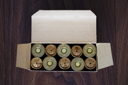 Old hunting shotgun shells in cardboard box, ammunition 12 gauge cartridges. Top view on dark wood...