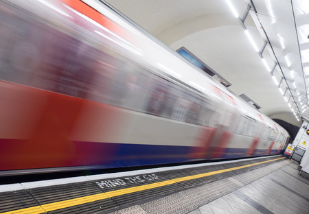 London, UK - April 4: Blurred fast moving underground train entering station. Mind The Gap warning in foreground.のeditorial素材