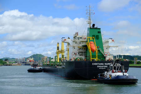 Panama Canal - Canal de Panama - Tugboats pulling a freighterのeditorial素材