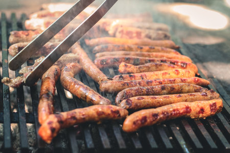 Grilled sausages with smoky char marks on a black barbecue grill.の写真素材