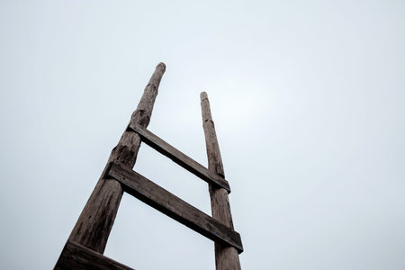 Creative background, wooden staircase leading to the sky. The concept of a career ladder, raising at work, the road to heaven, faith, career growth. Copy space.の写真素材