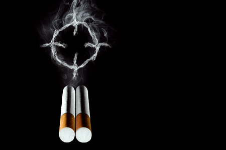 Cigarettes close-up on a black background, cigarette smoke, a target. Creative background. The concept of smoking kills, nicatine poisons, cancer from smoking, stop smoking. Copy space.の写真素材