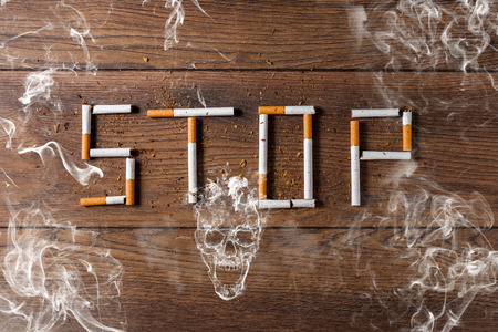 Creative background, the word stop is made up of cigarettes on a brown wooden background. The concept of smoking kills nicotine poisons. Copy space.の写真素材