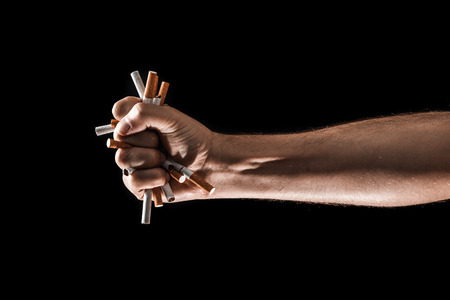 Creative background, male hand clenches a fist of a cigarette. The concept of smoking kills, stop smoking. Copy space.の写真素材