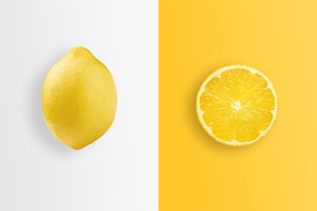 Creative background, lemon and lemon slices on a white and yellow background. Flat lay, copy space. The concept of nutrition, fresh fruit, natural products, juice.の写真素材