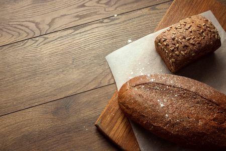 Creative background, freshly baked sliced rye bread on a wooden cutting board, flat lay, copy space. The concept of fresh pastry, black bread.の写真素材