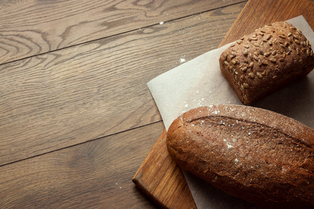 Creative background, freshly baked sliced rye bread on a wooden cutting board, flat lay, copy space. The concept of fresh pastry, black bread.の写真素材