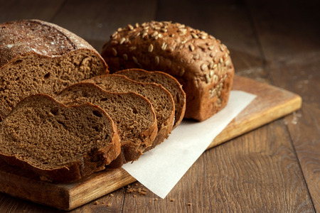 Creative background, freshly baked sliced rye bread on a wooden cutting board, flat lay, copy space. The concept of fresh pastry, black bread.の写真素材