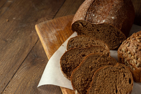 Creative background, freshly baked sliced rye bread on a wooden cutting board, flat lay, copy space....