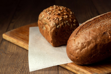 Creative background, freshly baked sliced rye bread on a wooden cutting board, flat lay, copy space. The concept of fresh pastry, black bread.の写真素材