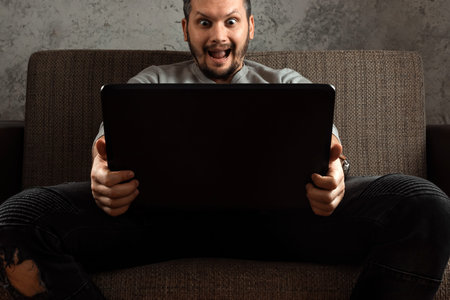 A man watches an adult video on a laptop while sitting on the couch. The concept of porn, men's...