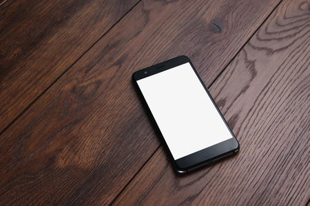 Creative background, smartphone with white screen on the background of wooden table mockup. The concept of preparation for design, mobile applications, mobile games, technology.の写真素材