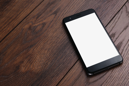 Creative background, smartphone with white screen on the background of wooden table mockup. The concept of preparation for design, mobile applications, mobile games, technology.の写真素材