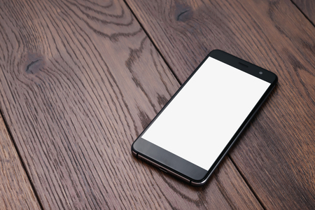 Creative background, smartphone with white screen on the background of wooden table mockup. The concept of preparation for design, mobile applications, mobile games, technology.の写真素材