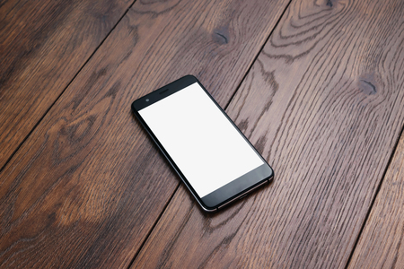 Creative background, smartphone with white screen on the background of wooden table mockup. The concept of preparation for design, mobile applications, mobile games, technology.の写真素材