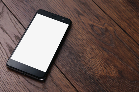 Creative background, smartphone with white screen on the background of wooden table mockup. The concept of preparation for design, mobile applications, mobile games, technology.の写真素材