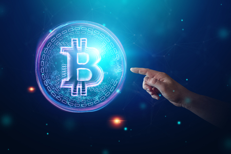 Male hand clicks on a bitcoin hologram, ultraviolet creative background. Cryptocurrency, electronic money, blockchain technology, finance, copy space.の写真素材