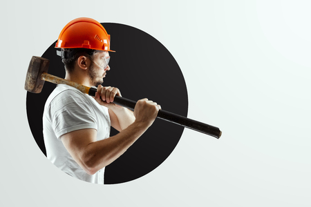 Male builder in orange helmet with sledge hammer isolated on white background. Concept building, contractor.の写真素材