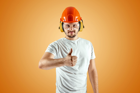 Male builder in orange helmet on an orange background. Concept of construction, contractor, repair.の写真素材