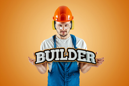 Male builder in orange helmet on an orange background. Concept of construction, contractor, repair.の写真素材