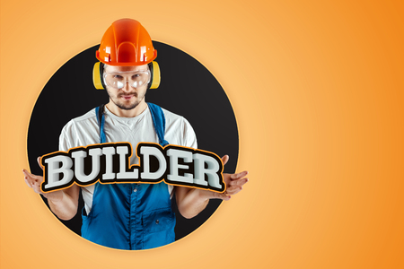 Male builder in orange helmet on an orange background. Concept of construction, contractor, repair.の写真素材